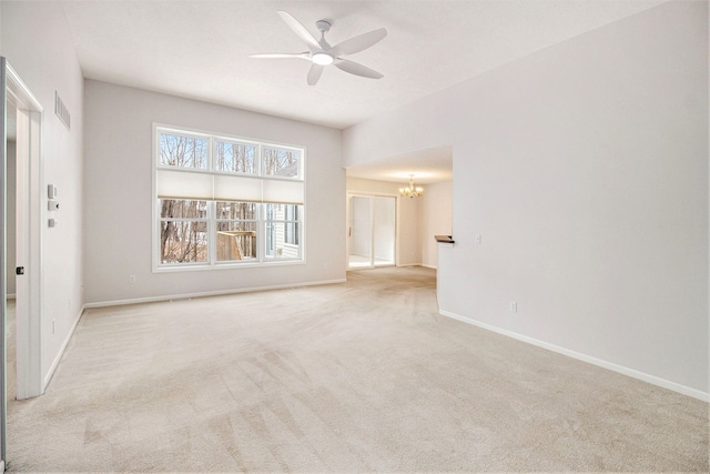 carpeted empty room featuring ceiling fan with notable chandelier