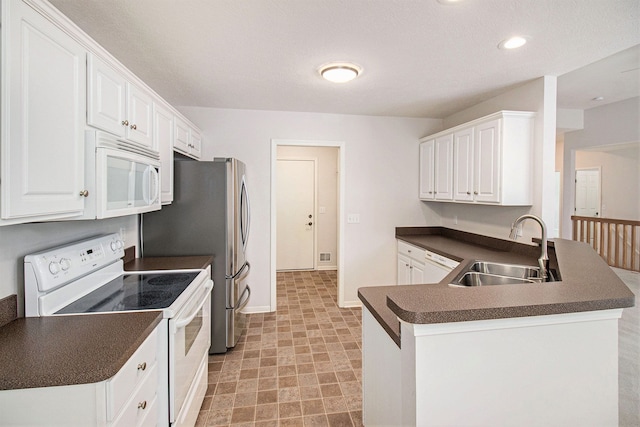 kitchen with white appliances, kitchen peninsula, sink, and white cabinets