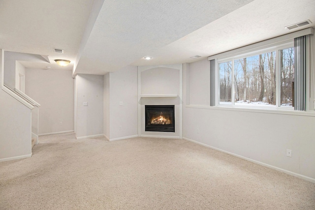 unfurnished living room featuring light carpet and a textured ceiling