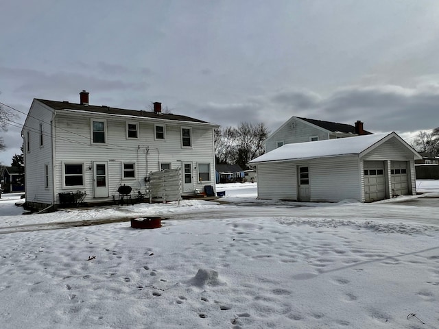 snow covered property with an outbuilding and a garage