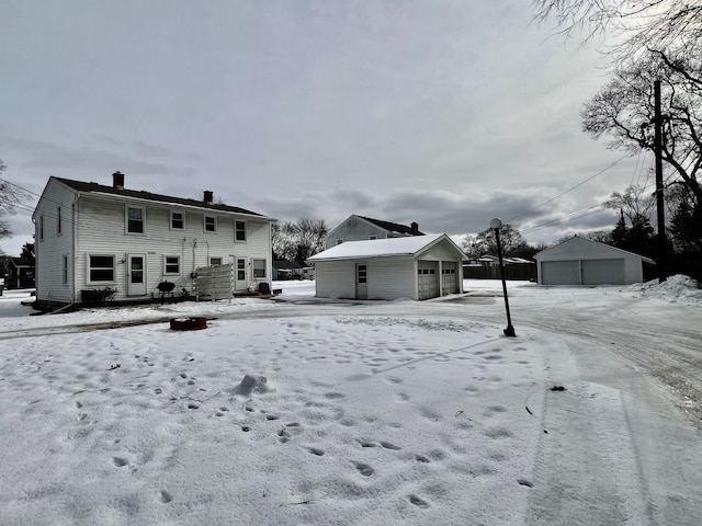 snow covered house featuring an outbuilding and a garage