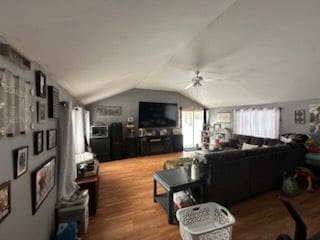 living room with hardwood / wood-style flooring, vaulted ceiling, and ceiling fan