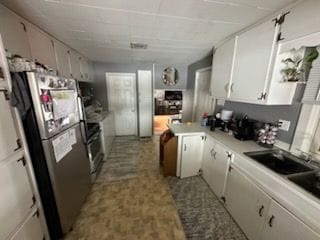 kitchen with white cabinetry, stainless steel fridge, and sink