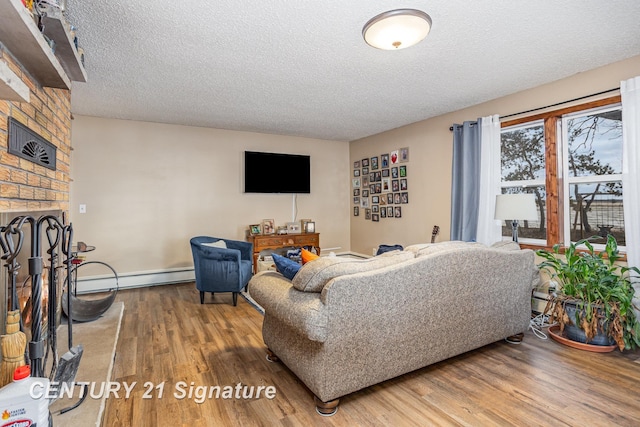 living room with a brick fireplace, hardwood / wood-style flooring, a textured ceiling, and baseboard heating