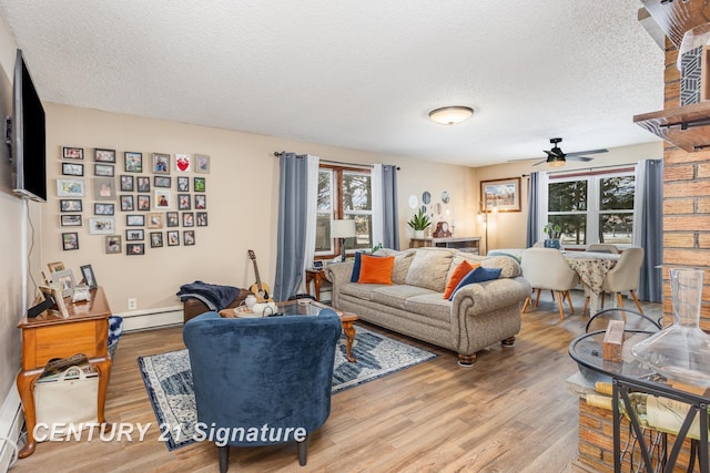 living room with ceiling fan, a baseboard radiator, light hardwood / wood-style floors, and a textured ceiling