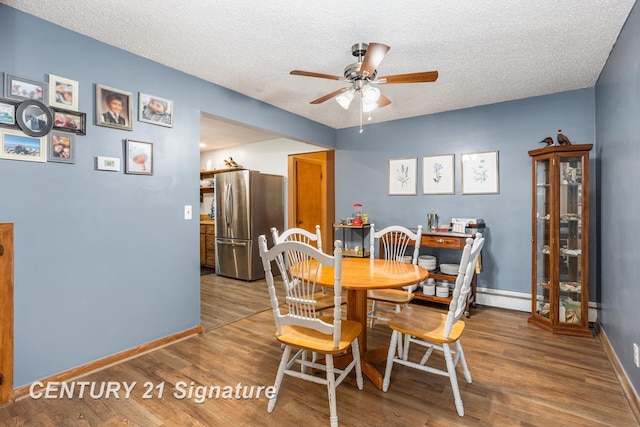 dining space with hardwood / wood-style flooring, ceiling fan, and a textured ceiling