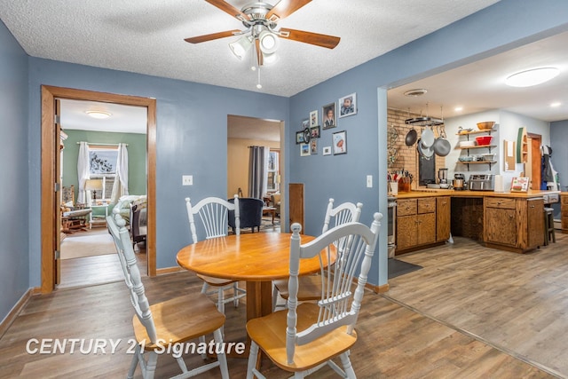 dining area with ceiling fan, light hardwood / wood-style floors, and a textured ceiling