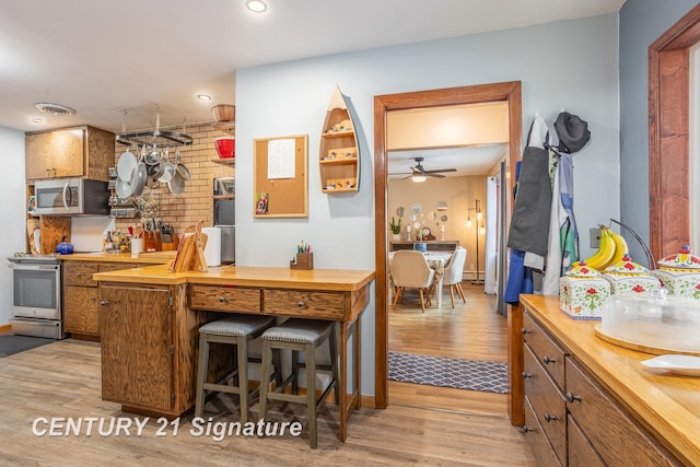 kitchen featuring ceiling fan, wood counters, appliances with stainless steel finishes, and light hardwood / wood-style flooring