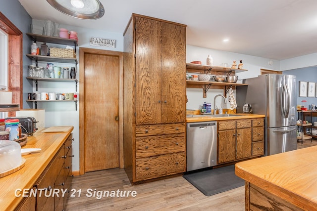 kitchen featuring appliances with stainless steel finishes, sink, butcher block countertops, and light hardwood / wood-style flooring