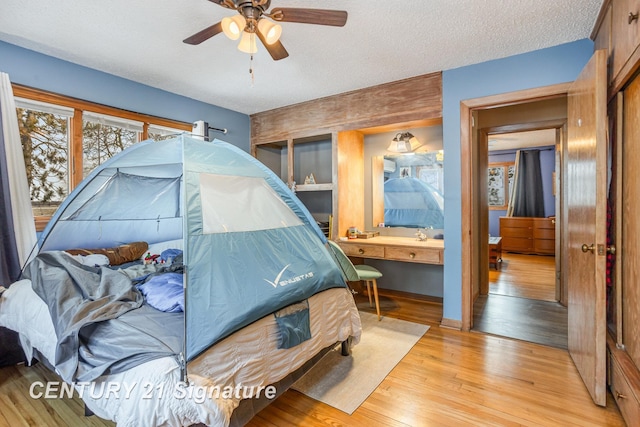 bedroom with ceiling fan, a textured ceiling, and light wood-type flooring