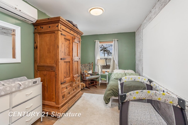 bedroom with an AC wall unit and light hardwood / wood-style floors