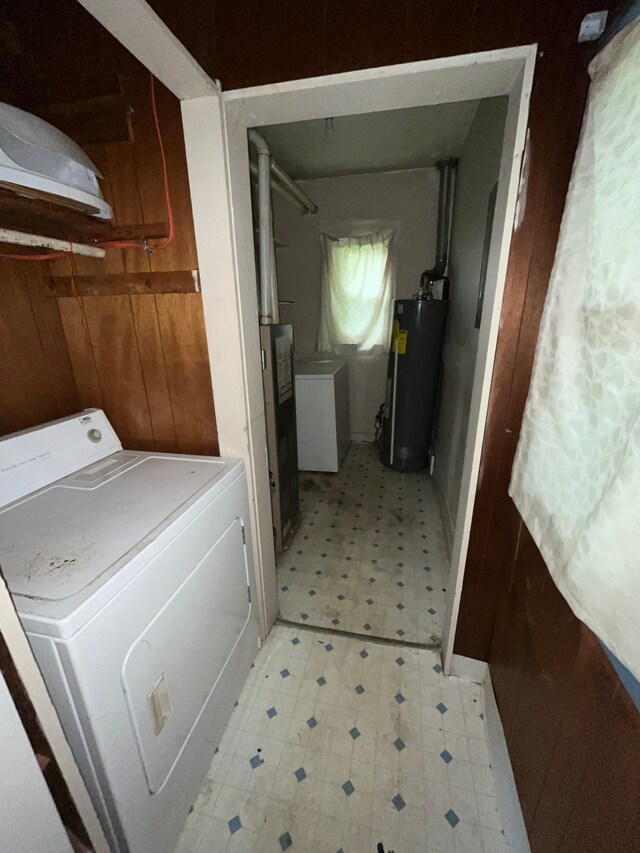 laundry area featuring gas water heater, washer / dryer, and wood walls