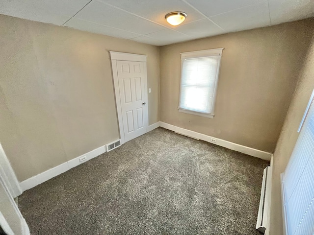 spare room featuring a baseboard heating unit and dark carpet