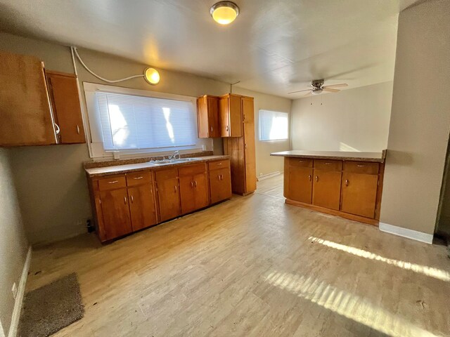 kitchen with ceiling fan, light hardwood / wood-style floors, sink, and kitchen peninsula