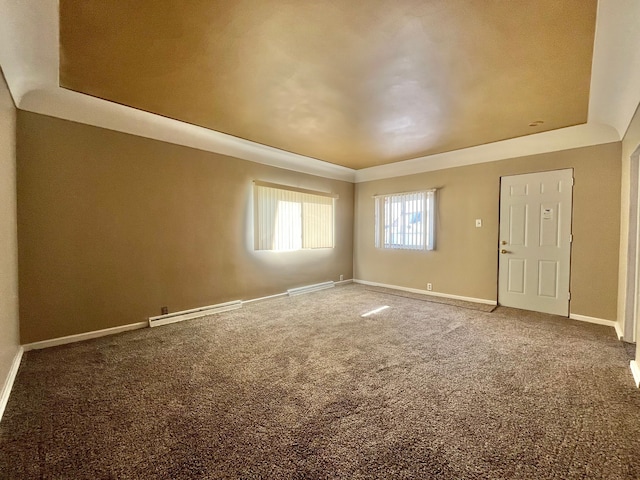 carpeted empty room with a tray ceiling and baseboard heating