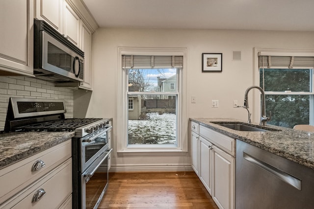 kitchen featuring sink, decorative backsplash, stone counters, and appliances with stainless steel finishes