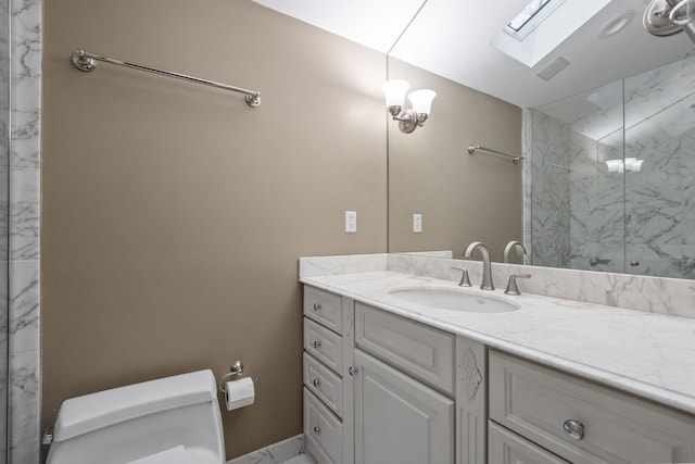 bathroom with tiled shower, vanity, toilet, and a skylight