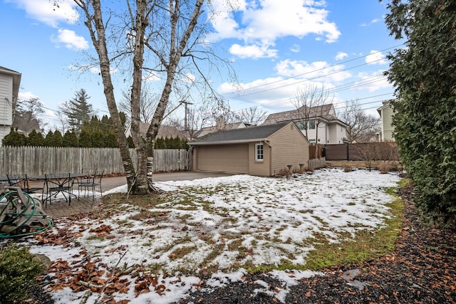 snowy yard with a garage and an outbuilding