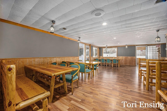 dining space featuring hardwood / wood-style floors and wooden walls