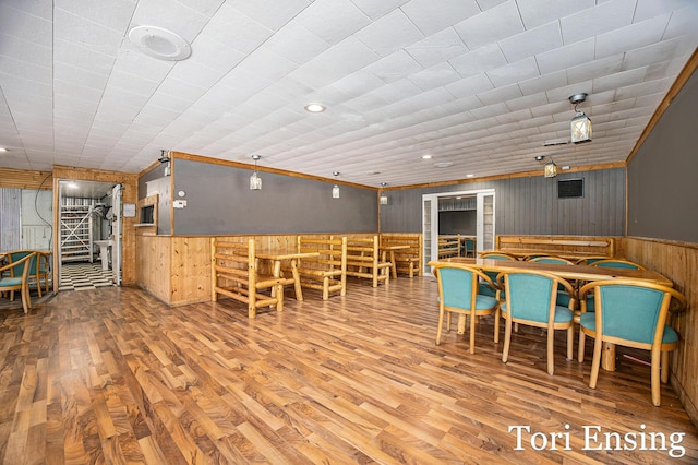 dining area featuring wood-type flooring and wood walls