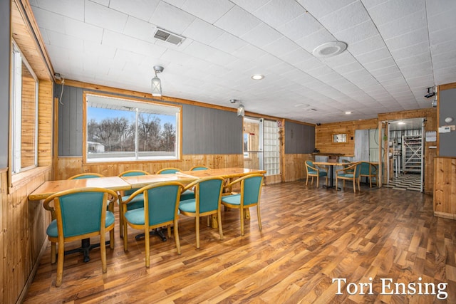 dining room featuring hardwood / wood-style floors and wood walls