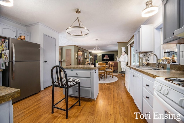 kitchen with sink, stainless steel refrigerator, light hardwood / wood-style floors, white cabinets, and white range with gas cooktop