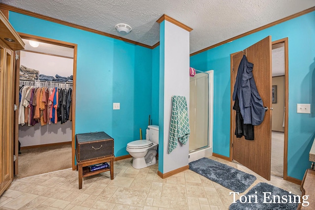 bathroom featuring crown molding, a shower with door, toilet, and a textured ceiling