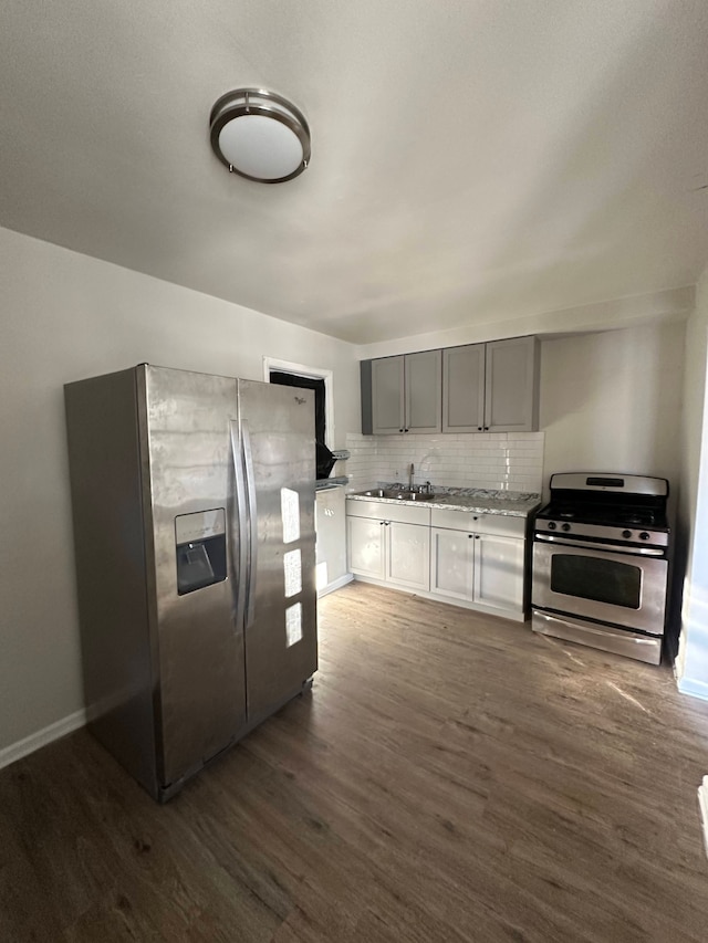 kitchen featuring dark hardwood / wood-style flooring, backsplash, sink, and appliances with stainless steel finishes