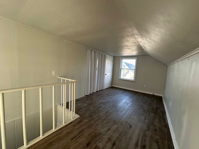 additional living space featuring lofted ceiling, dark hardwood / wood-style flooring, and a textured ceiling