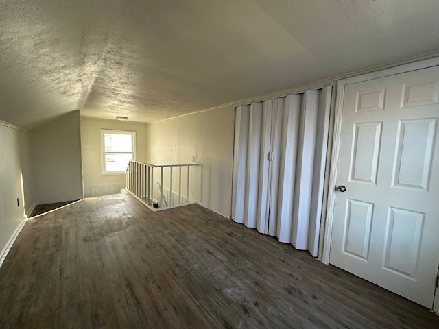 additional living space with lofted ceiling, dark hardwood / wood-style floors, and a textured ceiling