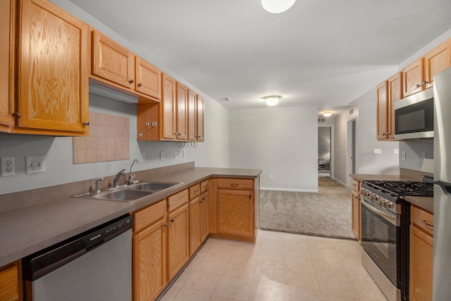 kitchen with light colored carpet, appliances with stainless steel finishes, kitchen peninsula, and sink