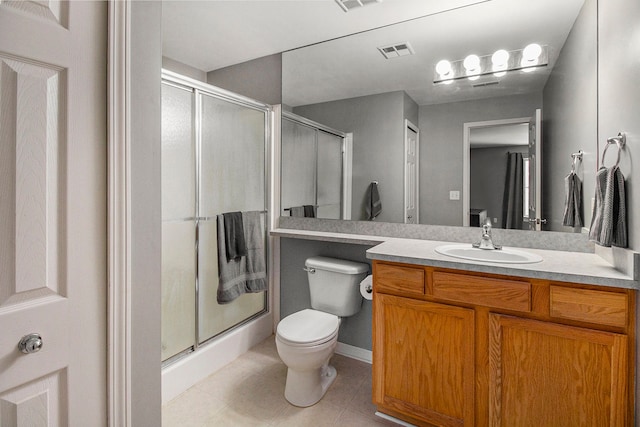 bathroom with vanity, tile patterned floors, a shower with door, and toilet