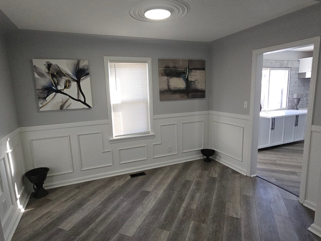 unfurnished room featuring a healthy amount of sunlight and dark hardwood / wood-style flooring