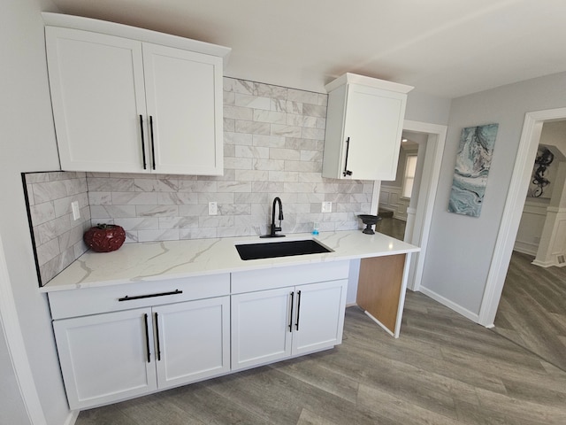 kitchen with light stone countertops, sink, and white cabinets