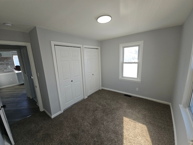 unfurnished bedroom with multiple closets and dark colored carpet