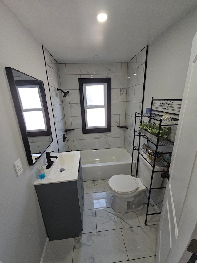 full bathroom featuring tiled shower / bath, vanity, and toilet