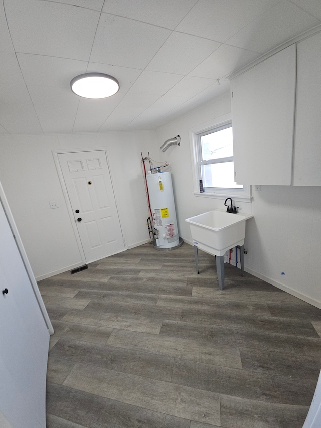 laundry room with sink, hardwood / wood-style flooring, and gas water heater