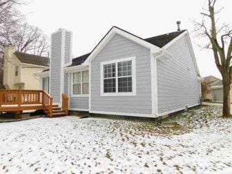 snow covered back of property with a wooden deck