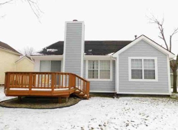 snow covered house featuring a chimney and a wooden deck