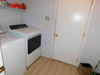 clothes washing area with laundry area, light wood-style flooring, and washer and clothes dryer