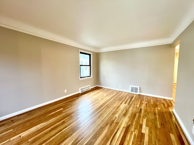 spare room with crown molding and light wood-type flooring