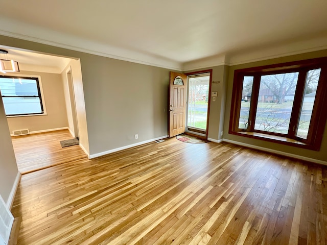 empty room featuring ornamental molding and light hardwood / wood-style flooring