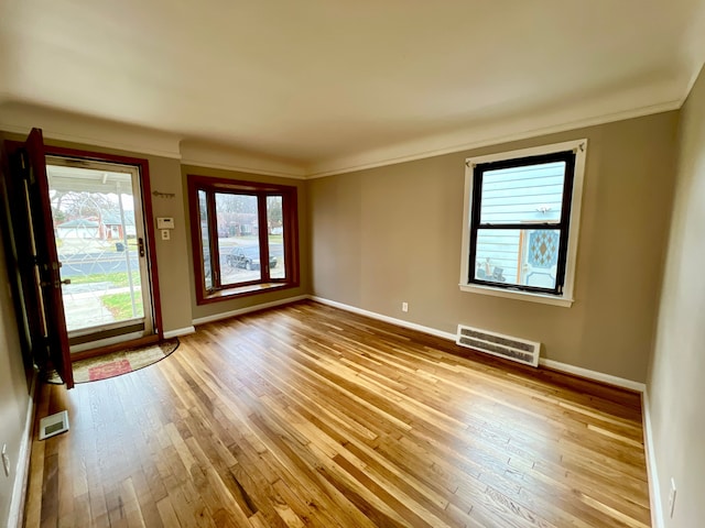 unfurnished room with crown molding and light wood-type flooring