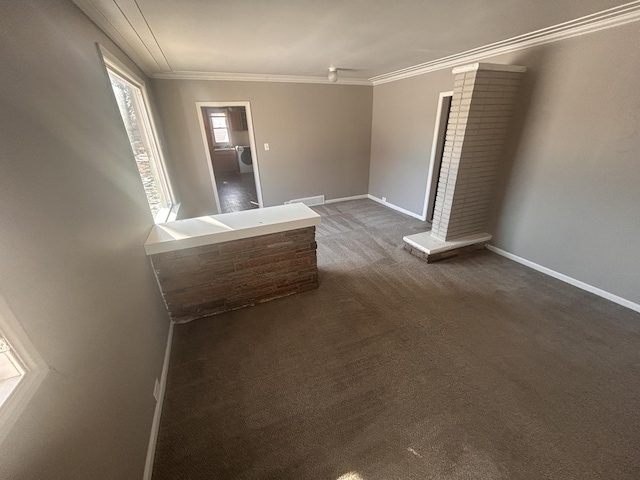 empty room featuring ornate columns, crown molding, and dark colored carpet