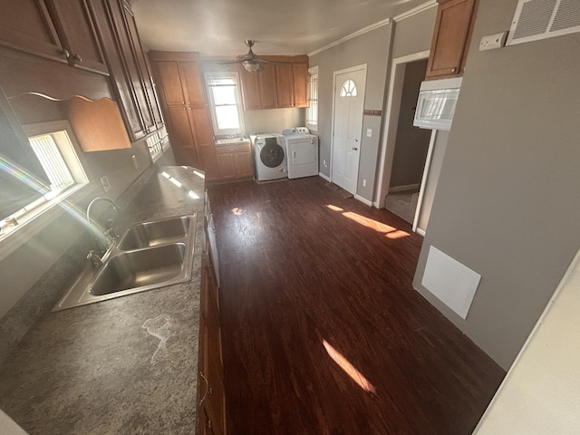 kitchen with sink, crown molding, dark hardwood / wood-style floors, ceiling fan, and washer and clothes dryer