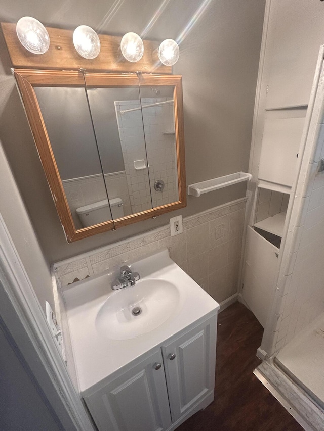 bathroom featuring tile walls, hardwood / wood-style floors, vanity, a shower, and toilet