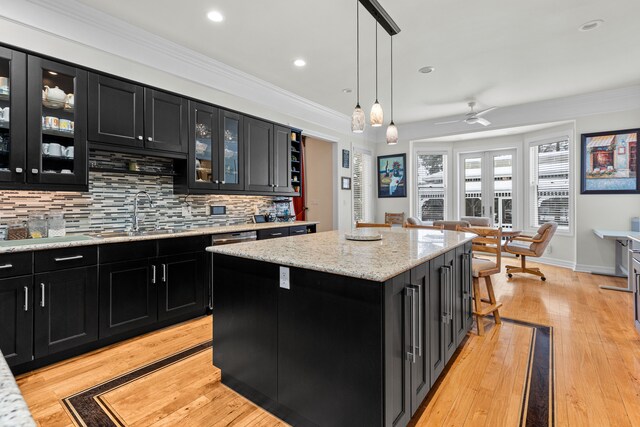 kitchen with hanging light fixtures, crown molding, a center island, and sink