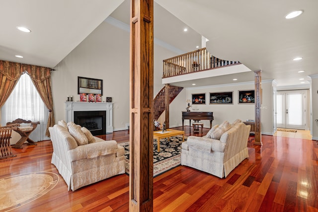 living room featuring crown molding, decorative columns, hardwood / wood-style floors, and a high ceiling