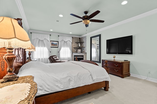 carpeted bedroom with ceiling fan, a large fireplace, and ornamental molding