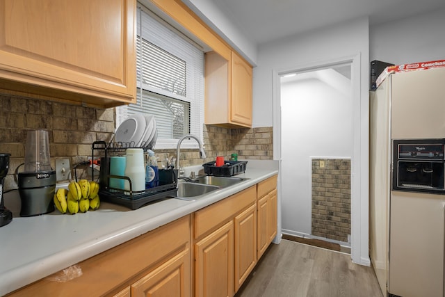 kitchen with light brown cabinetry, sink, light wood-type flooring, white fridge with ice dispenser, and decorative backsplash